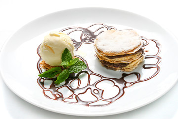 French dessert millefeuille, with chocolate syrup and vanilla ice cream on white background. Served with mint leaves on a white plate.