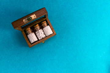 Top view image of wooden classic box with homeopathic medicine bottles on blue background. medicine  concept