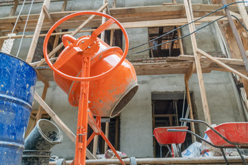 Orange concrete mixer prepares cement mortar. Concrete mixer, barrels against the background of a...