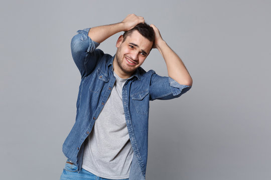Angry mad sad upset unshaven young man in denim jeans shirt posing isolated on grey wall background studio portrait. People sincere emotions lifestyle concept. Mock up copy space. Screaming gesturing.