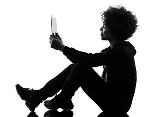 one mixed race african young teenager girl woman using digital tablet in studio shadow silhouette...