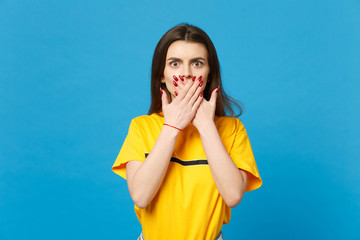Portrait of shocked young woman in vivid casual clothes looking camera, covering mouth with hands...