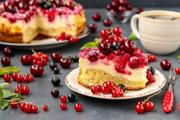 Summer cottage cheese cake with berries is located on a dark background, in the foreground piece of cake on a plate, horizontal photo