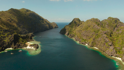 Naklejka premium Tropical landscape bay with beach and clear blue water surrounded by cliffs, aerial drone. El nido, Philippines, Palawan. Seascape with tropical rocky islands, ocean blue water. Summer and travel