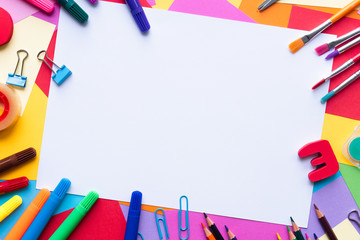 Colorful school supplies over a  paper background with place for your text