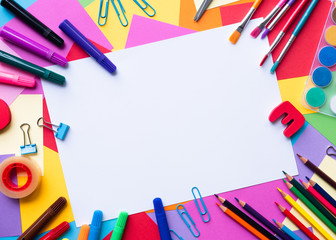 Colorful school supplies over a  paper background with copy space