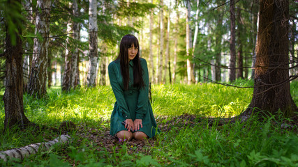 girl in green dress sitting in the woods