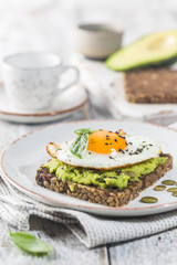 Sandwich with avocado, egg and spinach on white wooden background. Healthy diet breakfast