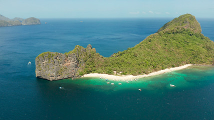 aerial view tropical beach on island with palm trees, blue lagoon and azure clear water. Helicopter Island in El Nido, Palawan Philippines. Tropical landscape with blue lagoon, coral reef