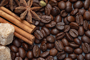Composition of coffee and cane sugar on a stone background with the addition of anise, cinnamon and cane sugar.
