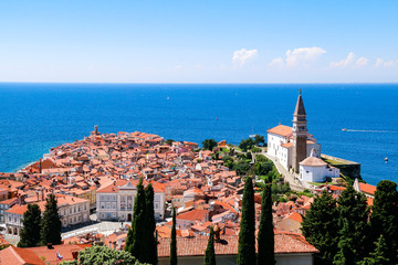 View of St George's Church and the red tiled rooftops of the old town of Piran in Slovenia, with the Adriatic Sea in the background