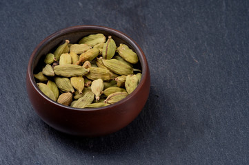 Cardamom in ceramic cup on stone background