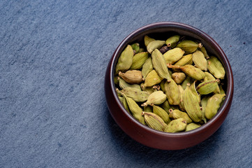 Cardamom in ceramic cup on stone background