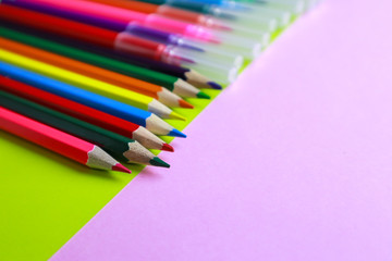 Colorful pencils and crayons on color background