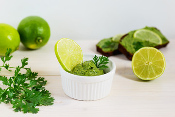 Guacamole from avocado, lime, cilantro and garlic on wooden table. 