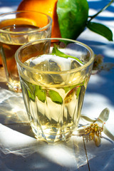 White wine served outside in garden on white table with fresh orange in sun lights