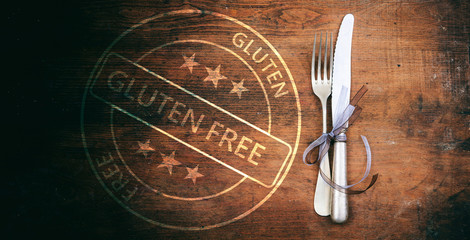 Gluten-free certification. Stamp and cutlery on rustic wooden table, top view.