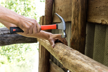 To hammer a nail with a hammer. Older worker carpenter