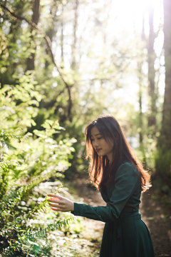 Young woman touching leaves in forest