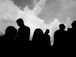 Fototapeta premium A black and white silhouette of a group of people with sky in the background