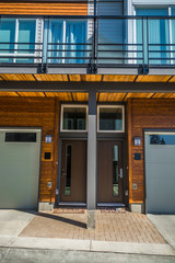 Entrance doors of brand new townhouses with wood textured wall on sunny day in British Columbia