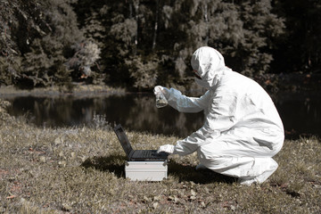 Ecological problem. Pollution. Examine oxygen. Scientist in protective mask and suit taking water...