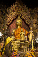 Altar with many golden Buddha statues at a Buddhist temple in Luang Prabang, Laos.