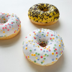 Top view of assorted donuts with chocolate frosted, pink glazed and sprinkles on a blue background.