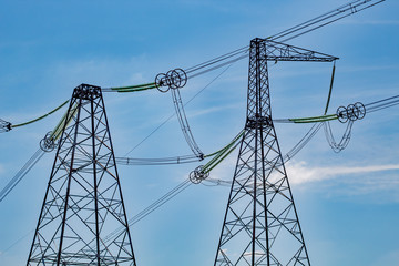 High voltage lines and reliance on a background of blue sky with clouds. Sunny day.