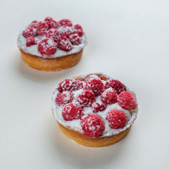 Top view cupcakes with wild strawberries and cream, fresh organic raspberries on white background. Homemade dessert close up.