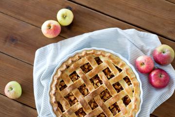 food, culinary and baking concept - apple pie and kitchen towel on wooden table