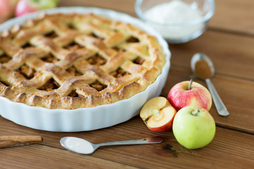 food, culinary and baking concept - close up of apple pie with cinnamon and sugar on wooden table