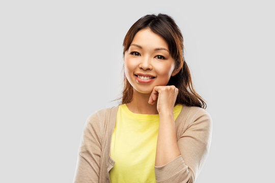 people, ethnicity and portrait concept - happy asian young woman over grey background