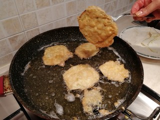 Woman's hand frying eggplant slices to prepear italian traditional food called Parmigiana 