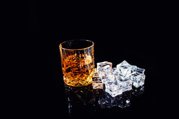 whiskey with ice cubes on black background