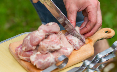  men's hands sliced marinated raw meat into pieces with a sharp metal knife