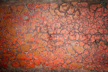 Background surface is red, terracotta with finely cracked paint, small cracks on the painted wall, craquelure