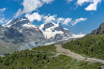 active senior woman, riding her electric mountainbike below the famous Gornergrat in Zermatt, in the background Rimpfischhorn and Strahlhorn,Wallis,Switzerland