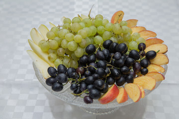 Peeling and pear in the plate. White table grapes on a crystal plate . Black and white grape in the pot.