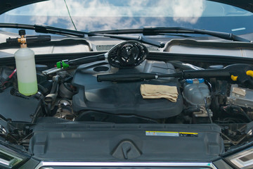 The open engine compartment of the car with accessories for washing. Close-up view