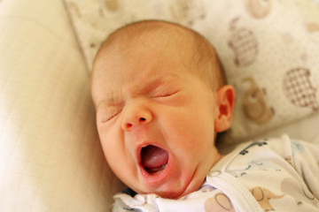 Cute newborn baby is yawing before going to bed.