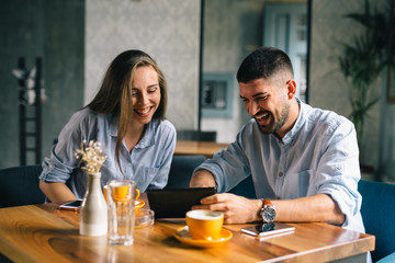 young couple using their tablet during a coffee date
