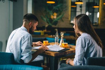 man and woman looking at menu's in cafeteria