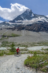 active senior woman, riding her electric mountainbike below the famous Matterhorn in Zermatt, Wallis,Switzerland