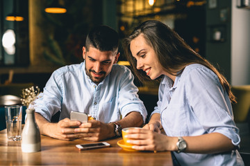 Fototapeta premium young couple using smartphone while enjoying their coffee at a cafe
