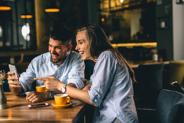 friends using smartphone while enjoying their coffee at a cafe
