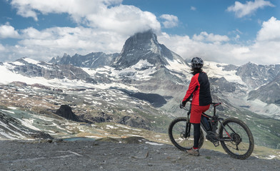 active senior woman, riding her electric mountainbike below the famous Matterhorn in Zermatt,...