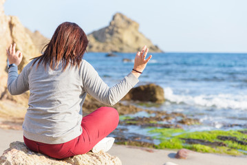 Young woman sitting on her back facing the sea with relaxation and meditation position. Healthy lifestyle. Happy life. Daily reflections