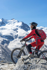 active senior woman, riding her electric mountainbikeon the Gornergrat in Zermatt,...