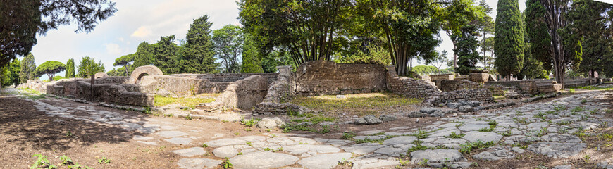 Fototapeta na wymiar Immersive panoramic 180 degree view from cobblestone pathway of ancient Roman necropolis landmark in the archaeological excavations of Ostia Antica - Rome
